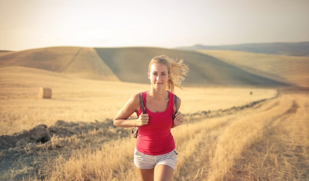 A woman jogging through vast, golden wheat fields under the summer sun, symbolizing freedom and adventure.