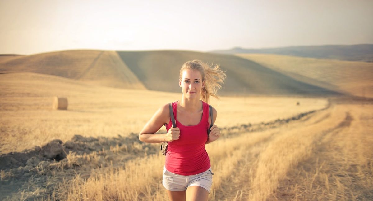 A woman jogging through vast, golden wheat fields under the summer sun, symbolizing freedom and adventure.